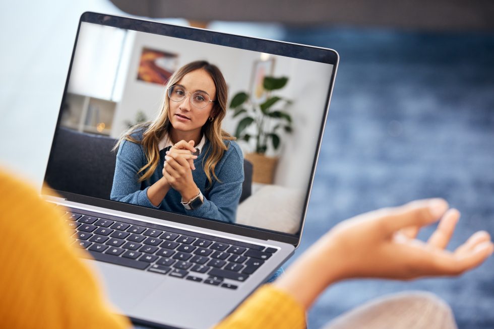 Woman using a laptop speaking to a therapist on a teleconference call.